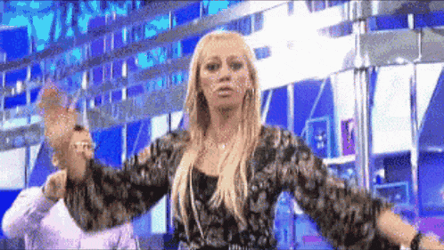 a woman in a floral shirt is dancing in front of a blue background