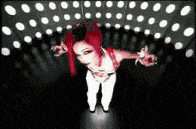 a woman with red hair and white pants is standing in a dark room