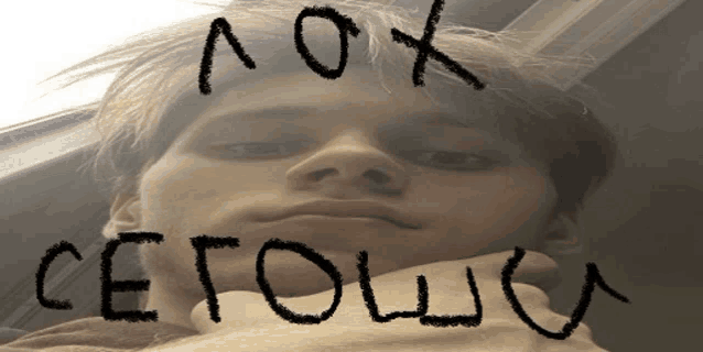 a close up of a man 's face with the words " aox cetowo " written on his forehead