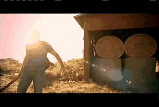 a man in a blue shirt is standing in front of a barrel