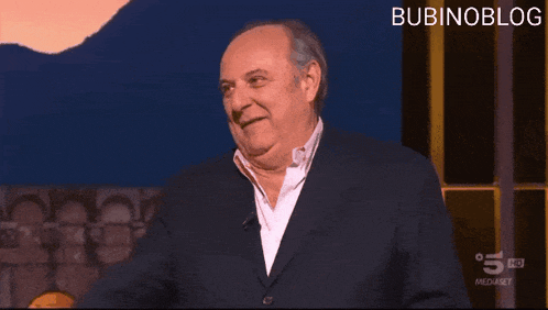 a man in a suit is laughing and pointing at the camera with bubinoblog in the corner