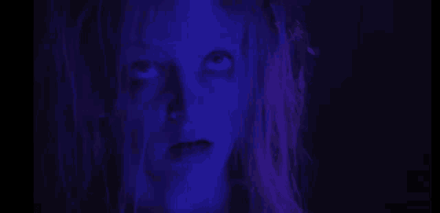 a close up of a woman 's face with purple hair and glowing eyes