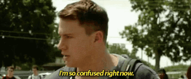 a man with a backpack is standing in front of a group of people and saying `` i am so confused right now '' .