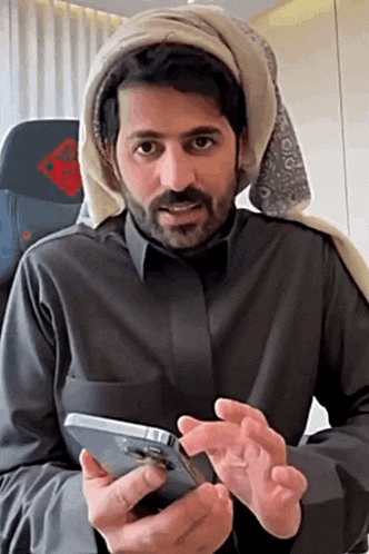 a man wearing a turban holds a cell phone