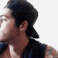 a man with a tattoo on his arm wearing a baseball cap