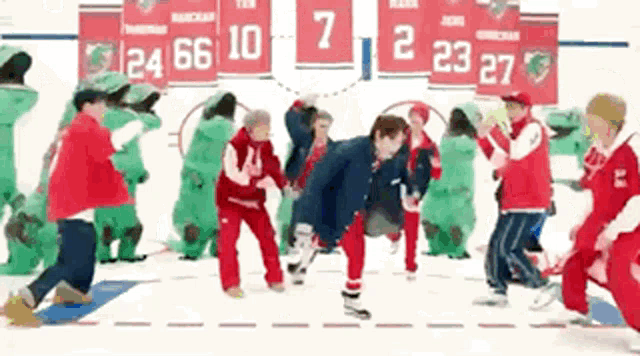 a group of people are dancing in front of a scoreboard with the numbers 7 and 2 on it .