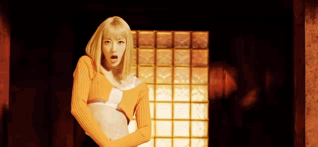 a woman with blonde hair is wearing an orange top