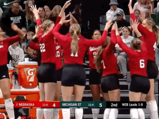 a group of volleyball players are giving each other a high five in front of a crowd .