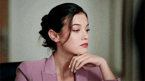 a woman with her hand on her chin looks to the side