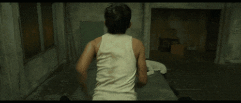 a man in a white shirt and black pants is running in a hallway
