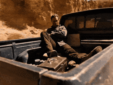 a man sits in the back of a truck with his feet up