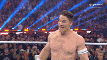 a man without a shirt is in a wrestling ring with a crowd watching .