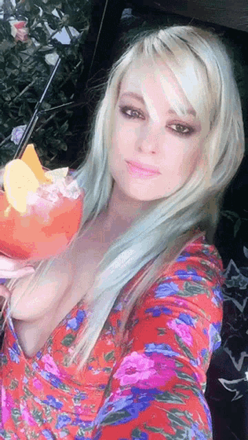 a woman in a floral dress is holding a drink in her hand