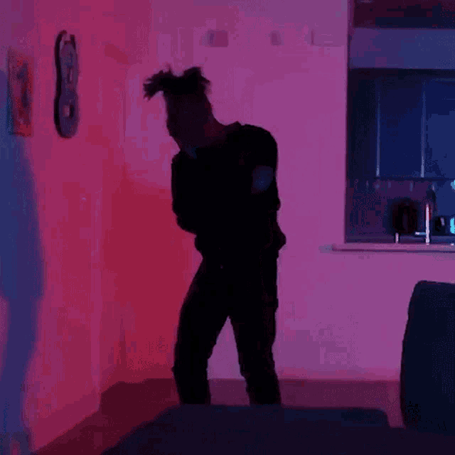 a man is standing in front of a pink wall with a guitar on it .