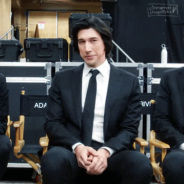 a man in a suit and tie sits in a director 's chair with the word ada on it