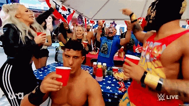 a group of people are gathered around a table with red cups and a sign that says ' w live ' on it