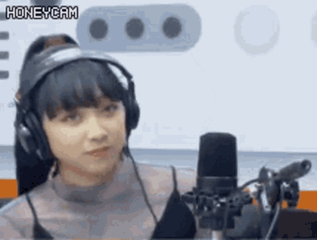 a woman wearing headphones and a microphone is sitting in front of a microphone .