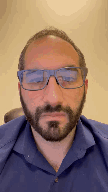 a man wearing glasses and a blue shirt is making a funny face
