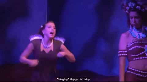 two women are dancing on a stage with the words happy birthday written on the bottom .