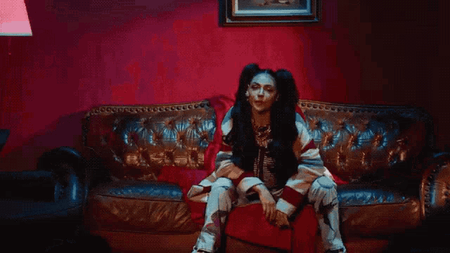 a woman with pigtails sits on a couch in a red room