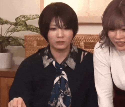 two women are standing next to each other and one of them is wearing a tie .