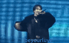a man singing into a microphone in front of a blue background with the words beyourluve below him