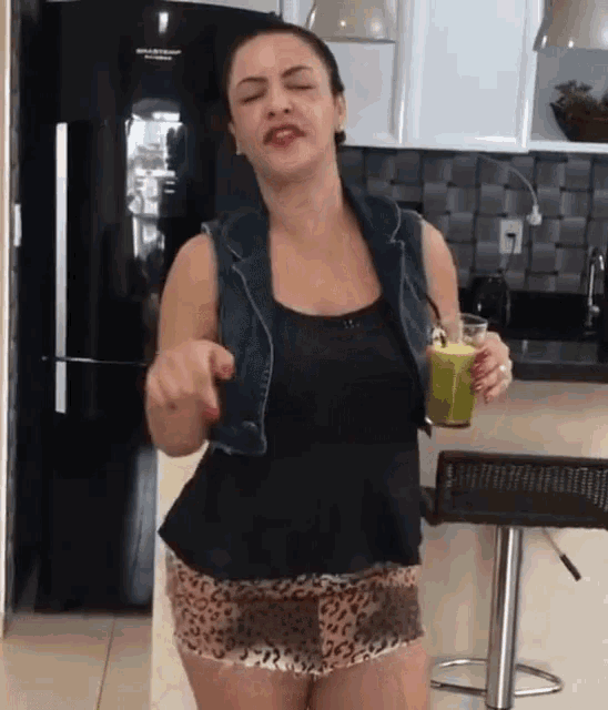 a woman in leopard print shorts is dancing in front of a black refrigerator