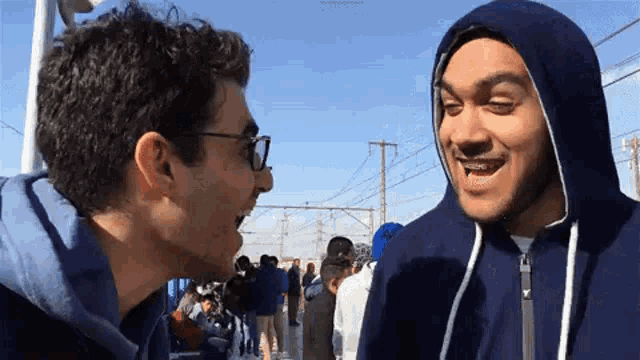 two men are standing next to each other and talking to each other .