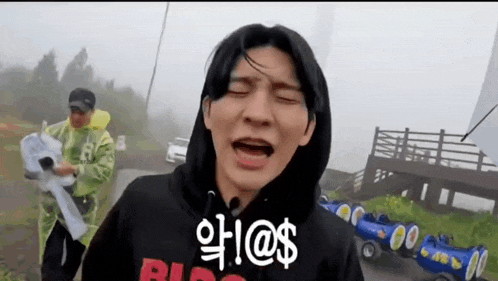 a man wearing a hoodie is making a funny face in front of a trolley .