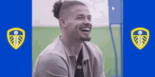 a man with a ponytail is laughing in front of a blue and yellow shield with the letters lfc on it