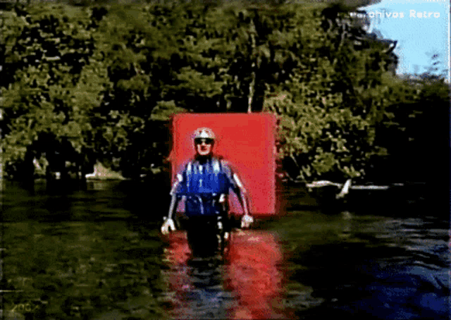 a man in a life jacket is walking through a body of water with archivos retro written in the corner