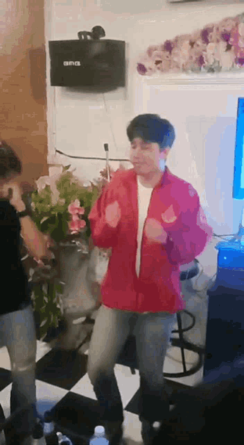 a man in a red jacket is dancing in front of a speaker that says ana on it