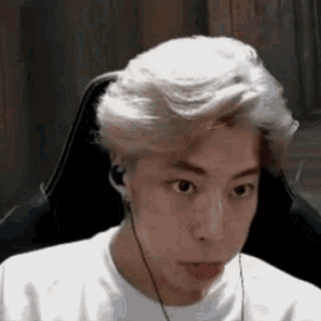 a young man is sitting in a chair wearing headphones and making a funny face .