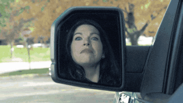 a woman is looking at her reflection in a side view mirror