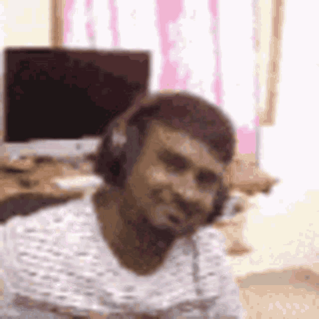 a man wearing headphones is sitting in front of a computer and smiling .