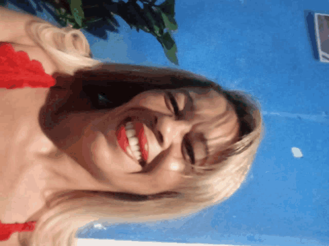 a woman with blonde hair and red lipstick is smiling with her eyes closed