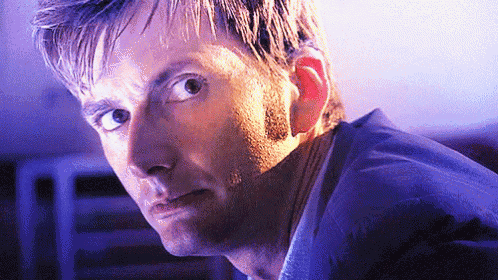 a close up of a man 's face with a purple light behind him