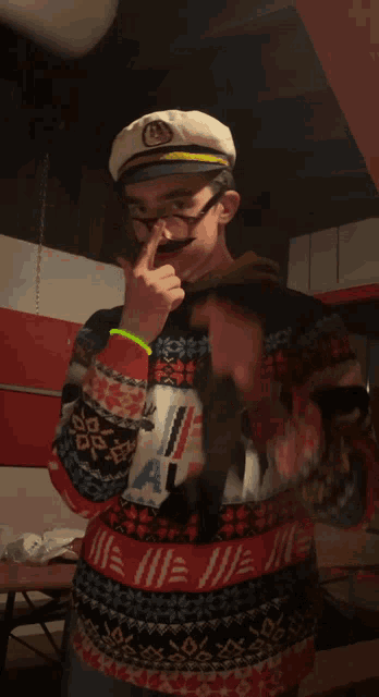 a man wearing a sweater with a moose on it and a captain hat