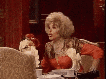 a woman is sitting at a table with plates and cups and talking to another woman .