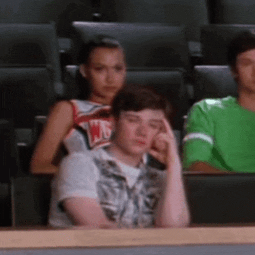 a girl in a cheerleading uniform is sitting next to a boy who is sitting in a stadium .