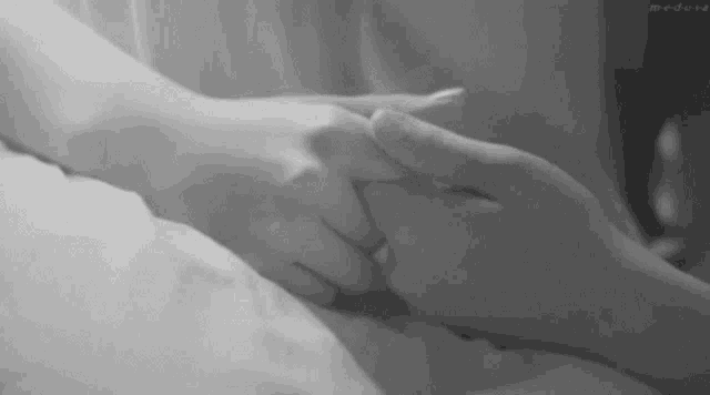 a black and white photo of a couple holding hands .