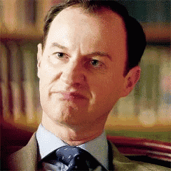 a man in a suit and tie is making a silly face .