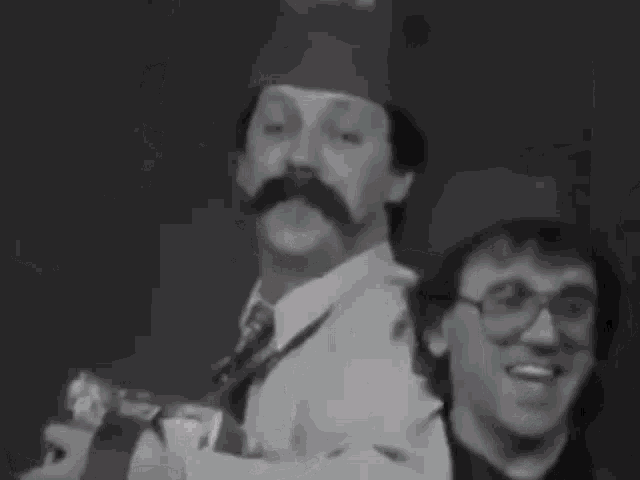 a man with a mustache is playing an accordion next to a young boy