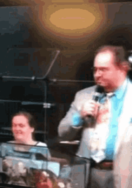 a man in a suit and tie is holding a microphone in front of a woman .