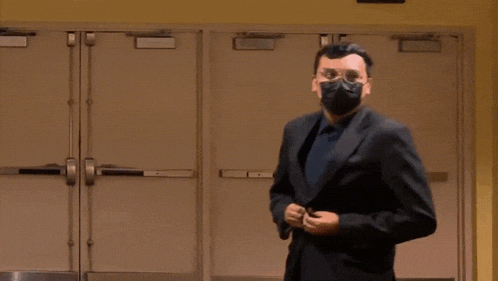 a man wearing a mask and glasses is standing in front of a row of doors