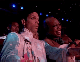 a man wearing a shirt that says prince is sitting next to a woman
