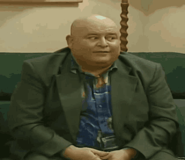 a man in a suit is sitting on a green couch