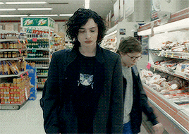 a man in a black shirt with a cat on it is walking in a grocery store