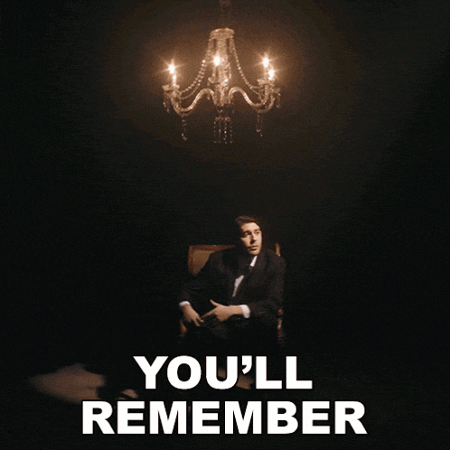 a man in a suit sits in front of a chandelier with the words " where you are "