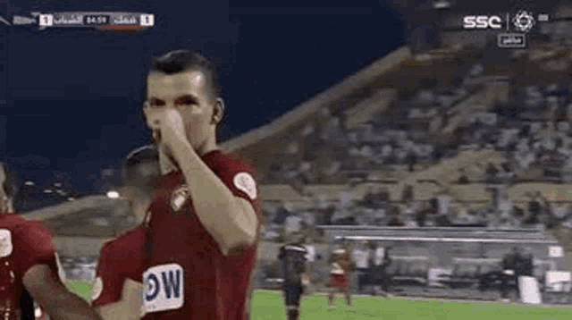 a soccer player is covering his face with his hand on a field .